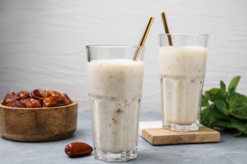 Glasses of delicious date smoothie and dried fruits on light grey table