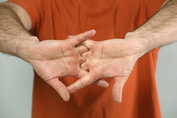 Man cracking his knuckles on light grey background, closeup. Bad habit