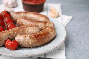 Plate with tasty homemade sausages and tomatoes on grey textured table, closeup. Space for text