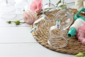 Plastic cups, hand pump and flowers on white wooden table, space for text. Cupping therapy