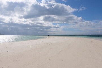 Fototapeta premium Solo person on a tiny, remote tropical island with white sand and beautiful turquoise ocean water in Papua New Guinea