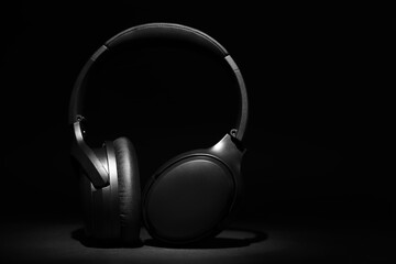 Fototapeta na wymiar Modern wireless headphones on black background, space for text