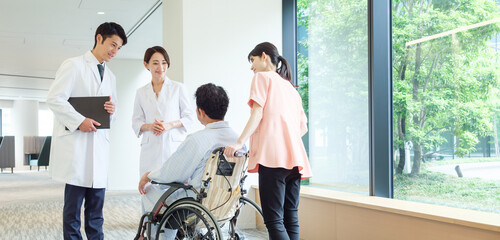 車椅子に乗った男性の患者と会話をする医師