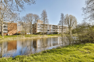 Obraz premium an apartment complex by the water's edge with trees in the foreground and buildings on the other side