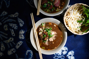 Rice noodles soup with pork, beef and vegetables, Thai boat noodles style, Table top view