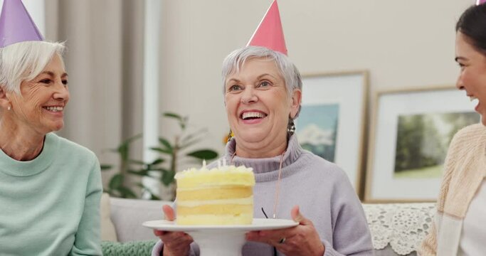 Birthday party, cake or applause with a senior woman blowing out candles with friends in the home living room. Celebration, milestone and clapping with a mature person enjoying a retirement event