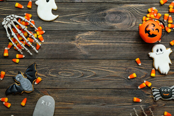 Tasty Halloween candy corns, skeleton hands and cookies on wooden background