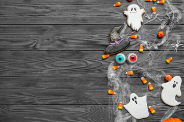 Composition with tasty Halloween candy corns and cookies on dark wooden background