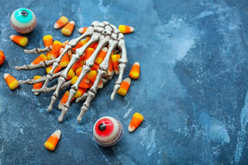Tasty Halloween candy corns, skeleton and eyes on blue background, closeup