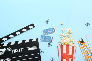 Composition tasty popcorn, clapperboard and cinema tickets on blue background. Halloween celebration