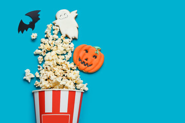 Composition with tasty popcorn and cookies on blue background. Halloween celebration