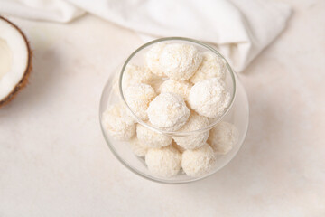 White chocolate candies with coconut topping in glass bowl on light table