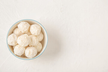 White chocolate candies with coconut topping in bowl on light table
