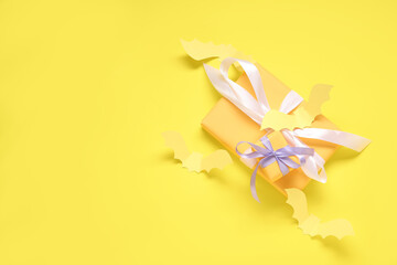 Composition with beautiful gift boxes and bats made of paper for Halloween on yellow background