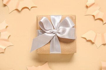 Composition with beautiful gift box and bats made of paper for Halloween on beige background, closeup