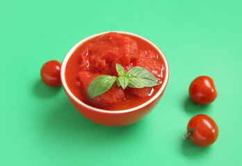 Bowl of canned tomatoes on green background