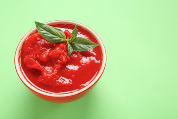 Bowl with canned tomatoes on green background
