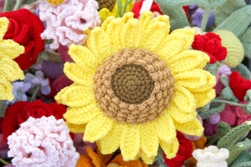 Close up on one beautiful crochet sunflower surrounded by smaller crochet flowers. Hand crafted.