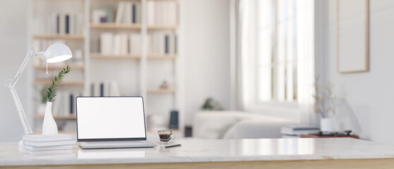 A laptop mockup on a tabletop with a blurred modern white living room as a background. - obrazy, fototapety, plakaty