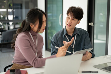 Two professional Asian office workers are discussing work, brainstorming on a project