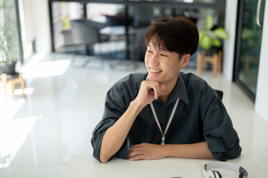 A smart Asian businessman is looking out the window, thinking and daydreaming