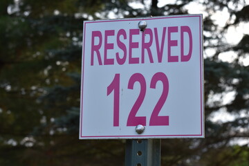 Reserved 122 Parking Sign, Red and White, with Tree Background in Wisconsin