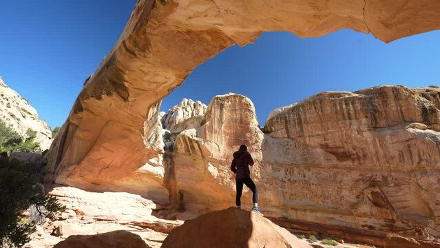 Lonely Woman Standing on Rock Under Natural Sandstone Arch, Hickman Bridge, Capitol Reef National Park, Utah USA