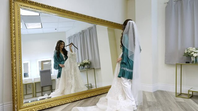 A roaming shot while a bride imagines herself wearing a wedding dress on her wedding day while looking in the mirror. Shot in 4k 60 fps.