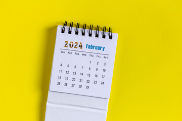 Desktop calendar for February 2024 on a yellow background.
