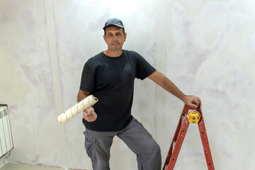 Male builder, master office, plasterer with a tool in working clothes
