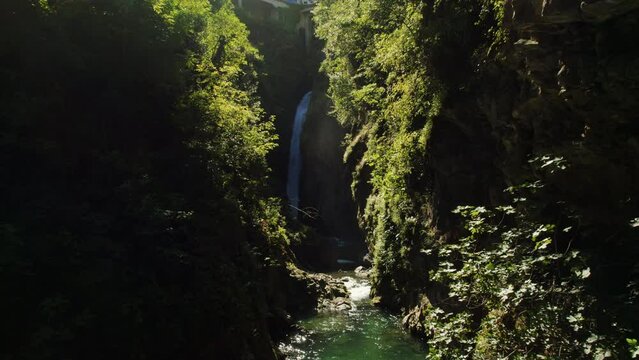 Waterfall in Nesso, Italy, at the end of a Canyon. The Gorge is covered by moss and plants, and the majestic waterfall at the back falls into the river heading to the lake