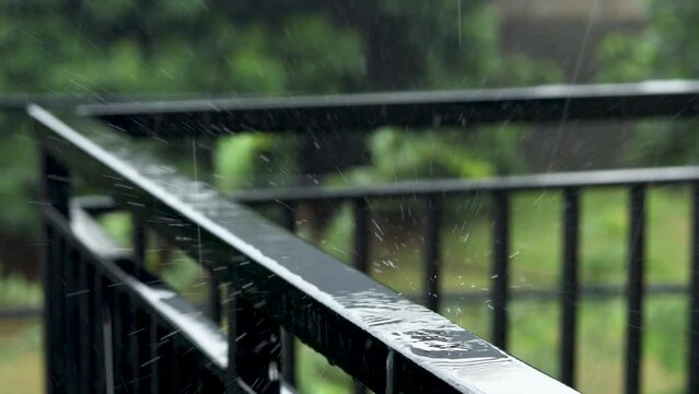 Drops of rain falling and splasing onto the stainless steel fence of the balcony.
