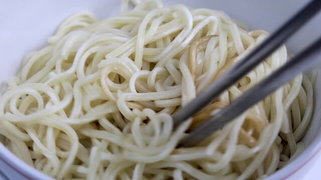 close up of chopstick stirring and mixing instant noodle in a bowl