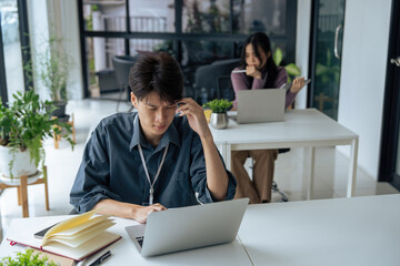 Tired stressed office worker sitting at desk and thinking, he is rubbing his eyes and feeling exhausted
