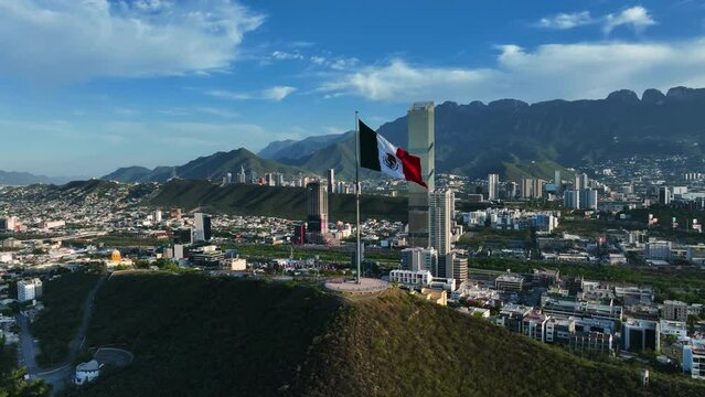 Aerial view around a mexican flag on top of the Cerro del Obispado, golden hour in Monterrey, Mexico