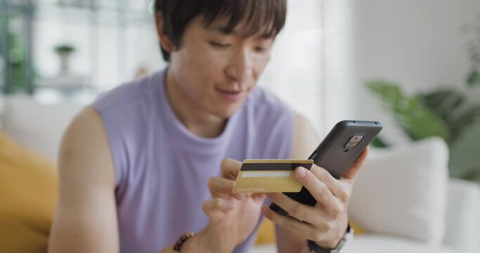 Gen Z Gay queer man non-binary pride at home. Asia LGBT young guy adult people happy relax sitting at sofa use omni channel easy buy now pay later BNPL shop store online bank loan. Cash sale discount.