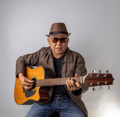 Obraz premium Asian senior man playing guitar happily, studio shot white background