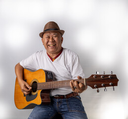 Asian senior man playing guitar happily, studio shot white background