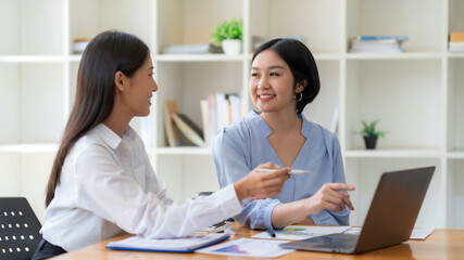 Obraz premium Two young Asian businesswoman consult and talk analysis of marketing planning with laptop computer.