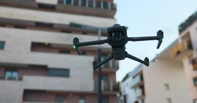 Close-up of Mavic quadcopter drone in static flight with residential buildings in background