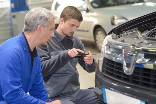 student with instructor repairing a car during apprenticeship