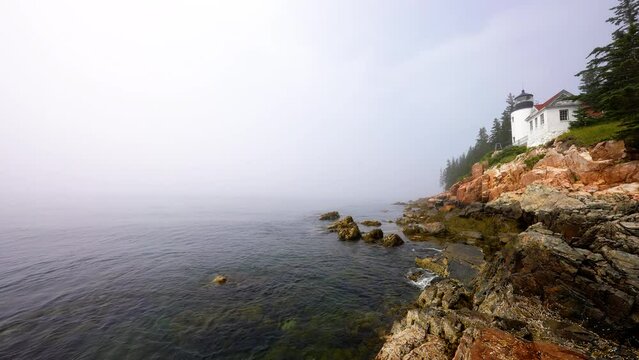 wide shot of Acadia Bass Harbor lighthouse on a foggy morning with sound audio of waves crashing ashore shoreline