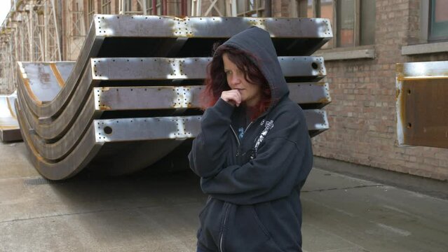 Mysterious Girl in a hoodie standing and looking around trying to hide her identity. Medium shot slow motion.