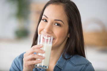 beautiful woman in home kitchen holding glass of milk