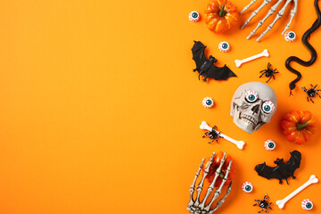 Happy Halloween flat lay composition. Pumpkins, bloody eyes, skeleton hands, bats, bones, skull on orange background.