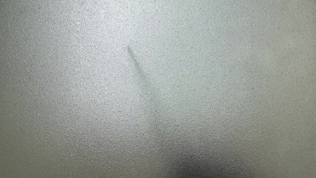 Male hand silhouette shadow behind translucent mirror holding knife moving slowly 