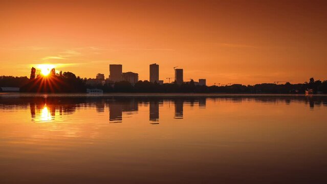 Sunrise over Bucharest office buildings. 4K time lapse video during a beautiful summer sunrise over Herastrau Lake in Bucharest, Romania.