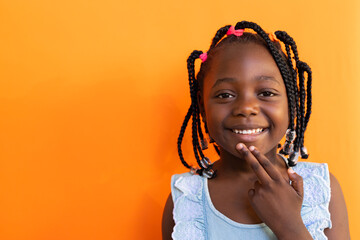 African american schoolgirl doing sign language gestures over orange background at elementary school