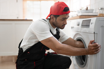 Asia man workers in uniform fixing washing machine in the kitchen at home	