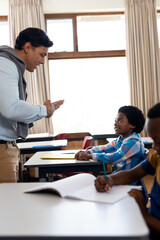 Obraz premium Diverse male teacher teaching school boy using sign language in class at elementary school